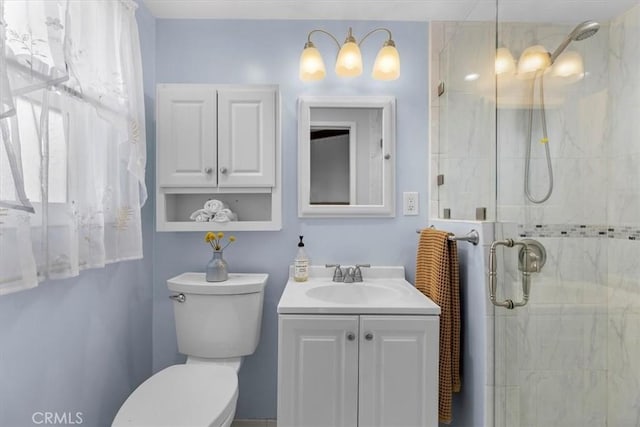 bathroom featuring vanity, toilet, and a shower with door