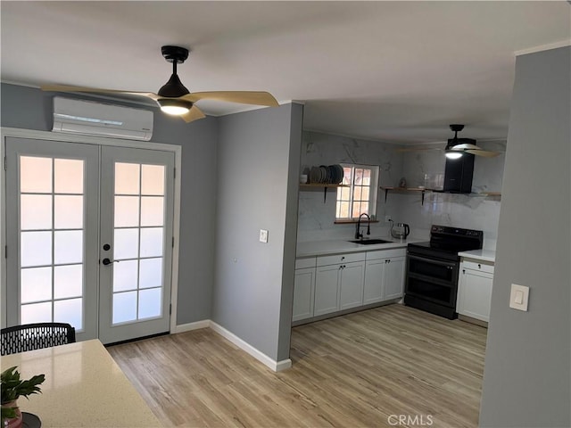 kitchen featuring french doors, black electric range oven, sink, a wall mounted AC, and white cabinets