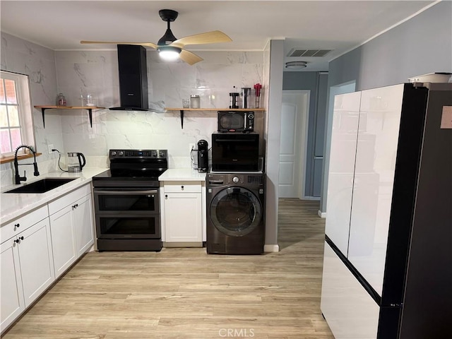 kitchen with sink, wall chimney range hood, white cabinetry, black appliances, and washer / dryer