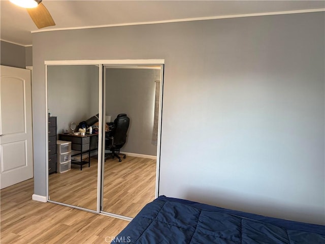 bedroom featuring crown molding, light hardwood / wood-style floors, a closet, and ceiling fan