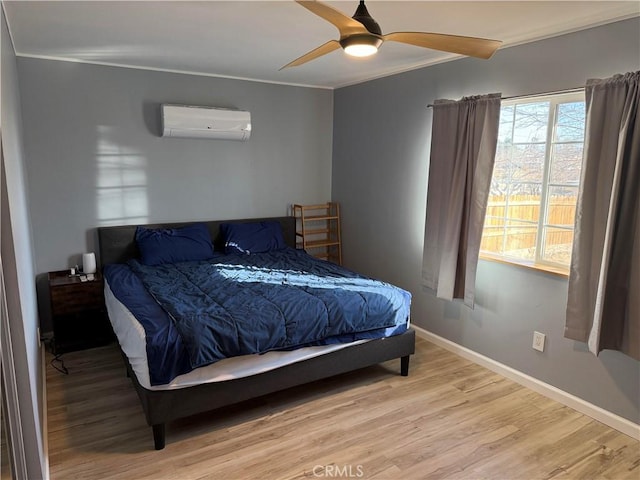 bedroom featuring crown molding, light wood-type flooring, ceiling fan, and a wall unit AC