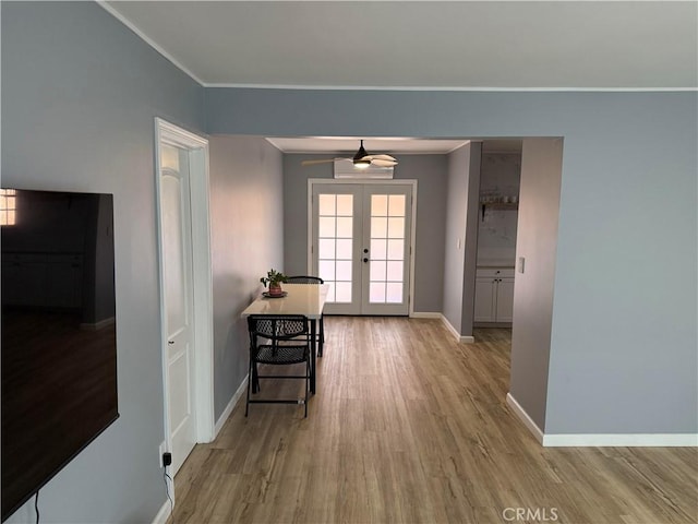 hallway featuring ornamental molding, light wood-type flooring, and french doors