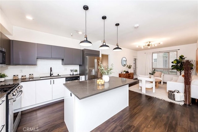 kitchen featuring a kitchen island, appliances with stainless steel finishes, sink, white cabinets, and hanging light fixtures