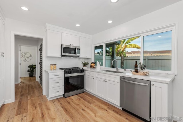 kitchen with backsplash, stainless steel appliances, sink, and white cabinets