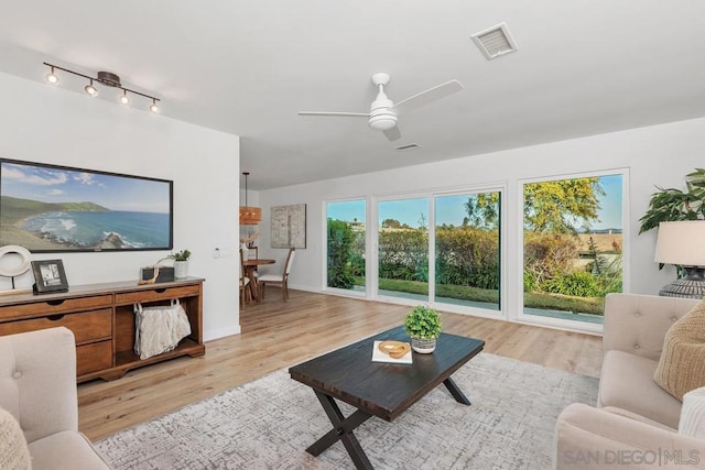 living room with light hardwood / wood-style floors, rail lighting, and ceiling fan