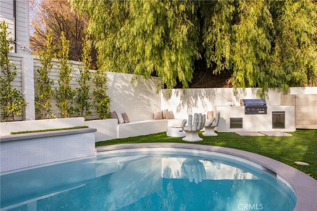 view of pool featuring grilling area, a yard, and exterior kitchen