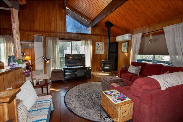 living room featuring a wood stove, an AC wall unit, wooden walls, a wealth of natural light, and beam ceiling