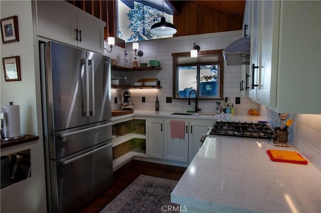 kitchen featuring sink, appliances with stainless steel finishes, white cabinetry, light stone counters, and decorative backsplash