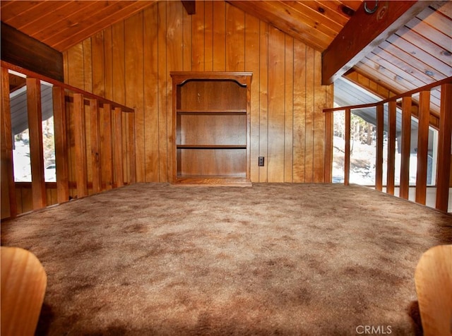 unfurnished living room with vaulted ceiling with beams, wooden walls, and a healthy amount of sunlight