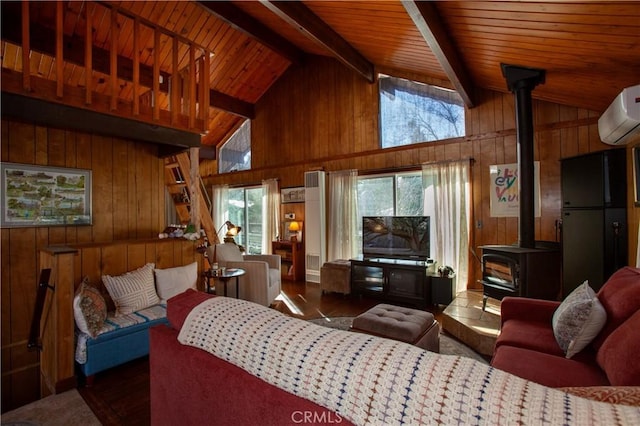 living room featuring a wall mounted air conditioner, wooden walls, lofted ceiling with beams, and a wood stove