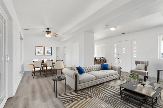 living room with ceiling fan, visible vents, baseboards, and light wood-style flooring