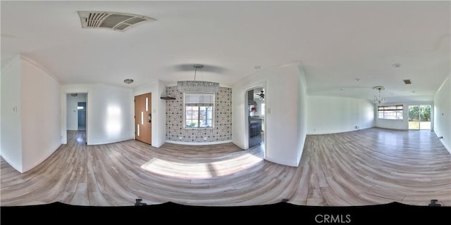 unfurnished living room with a chandelier and light hardwood / wood-style floors