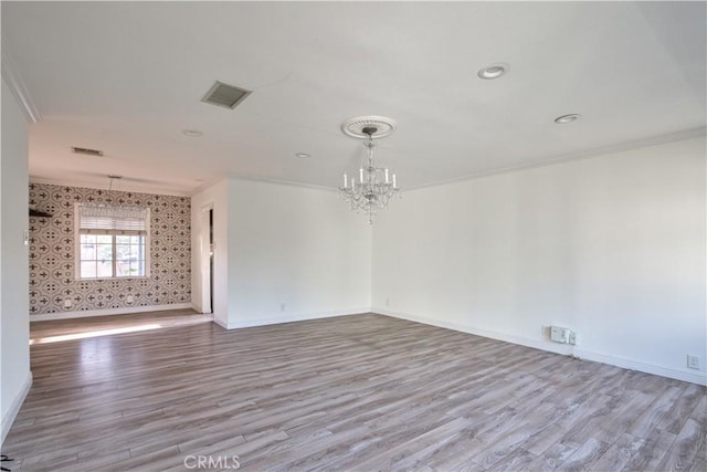 unfurnished room with an inviting chandelier, crown molding, and light hardwood / wood-style flooring