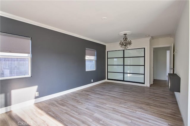 unfurnished room featuring an inviting chandelier, crown molding, and hardwood / wood-style flooring