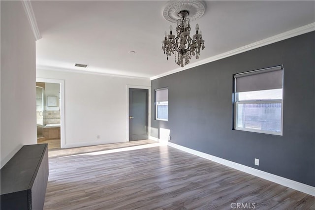 spare room featuring crown molding, a notable chandelier, and hardwood / wood-style flooring