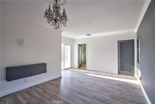 spare room featuring crown molding, a chandelier, and hardwood / wood-style flooring