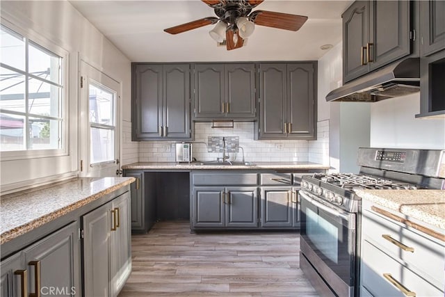 kitchen with gray cabinets, gas stove, sink, and decorative backsplash