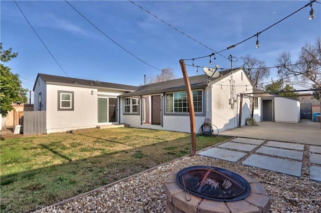 back of property featuring a storage shed, a lawn, and a fire pit