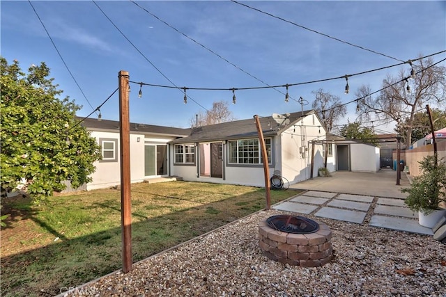 rear view of property with an outbuilding, a lawn, and an outdoor fire pit