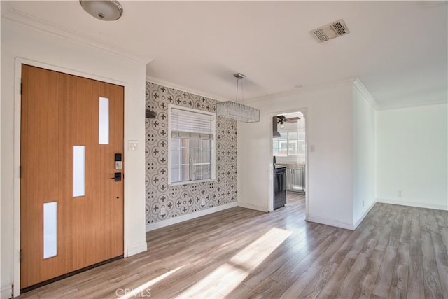 foyer entrance with crown molding and light hardwood / wood-style flooring