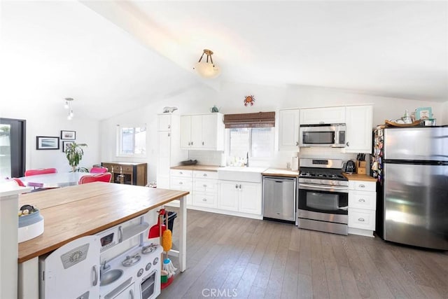 kitchen with appliances with stainless steel finishes, butcher block countertops, a sink, and white cabinets