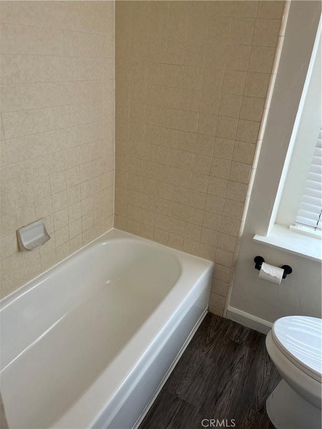 bathroom with toilet, baseboards, and wood finished floors