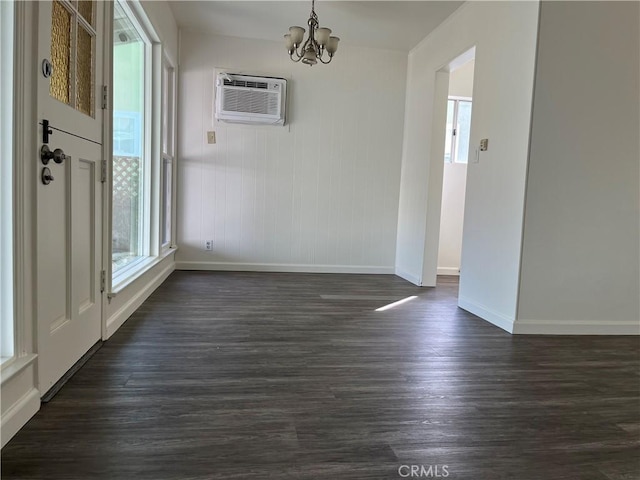 unfurnished dining area featuring a wall unit AC, dark wood-style floors, a wealth of natural light, and an inviting chandelier