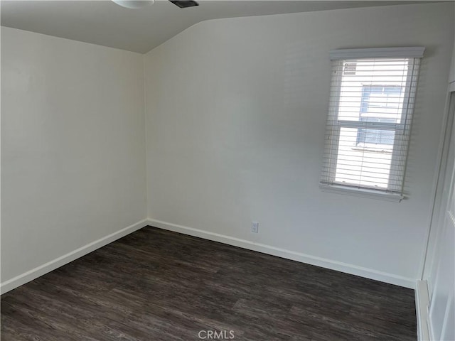 spare room featuring dark wood-style floors, lofted ceiling, a wealth of natural light, and baseboards