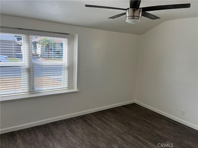 spare room with dark wood-style floors, ceiling fan, vaulted ceiling, and baseboards