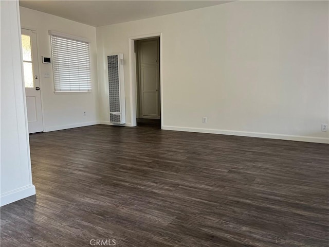 spare room with dark wood-style flooring and baseboards