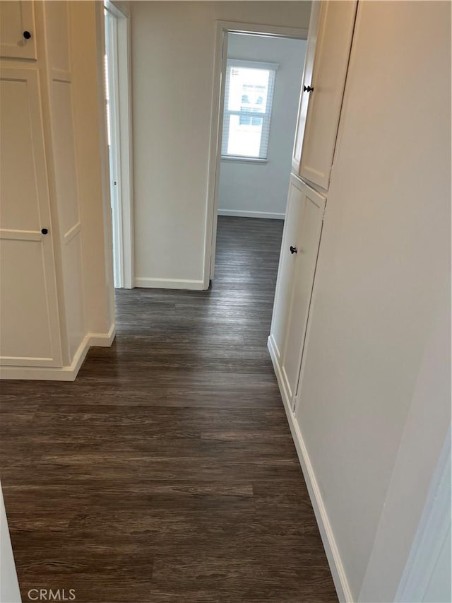 hallway featuring dark wood-style flooring and baseboards