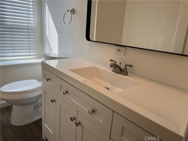 half bathroom featuring toilet, wood finished floors, and vanity