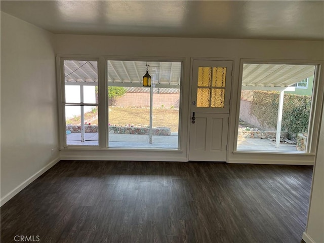 doorway to outside featuring baseboards and dark wood-style flooring