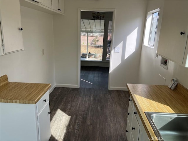 kitchen with dark wood-style floors, baseboards, white cabinets, and a sink