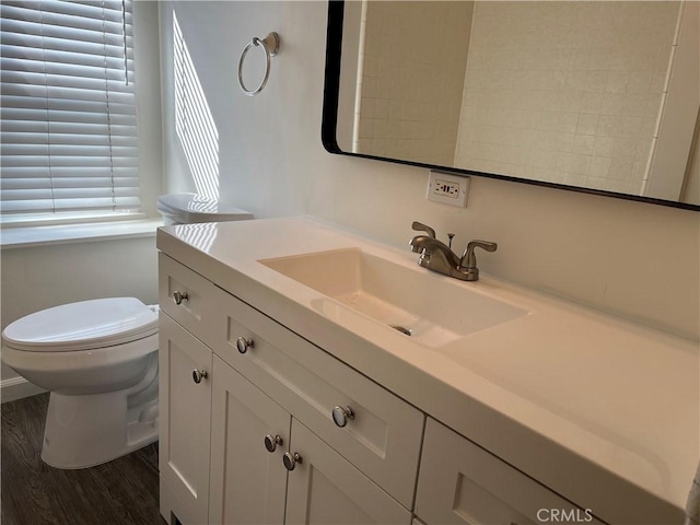 half bathroom with vanity, toilet, and wood finished floors