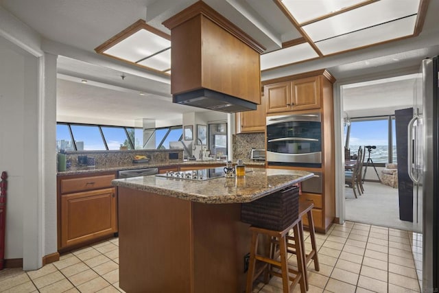 kitchen with a kitchen island, a kitchen bar, decorative backsplash, light tile patterned floors, and stainless steel appliances