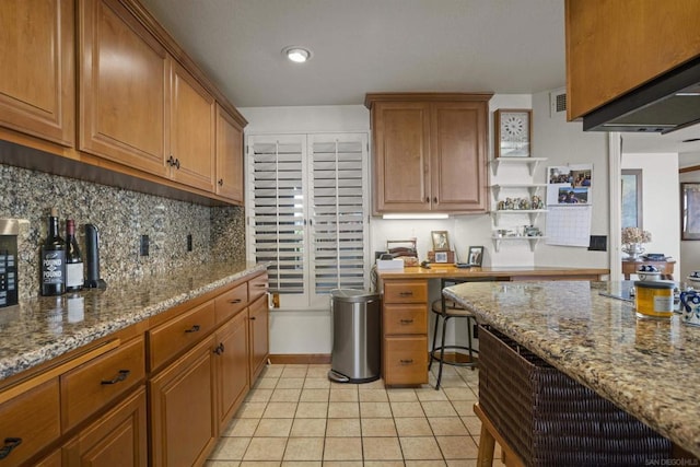 kitchen featuring tasteful backsplash, light tile patterned flooring, and light stone countertops