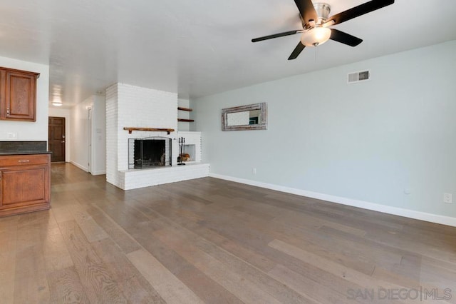 unfurnished living room featuring hardwood / wood-style flooring, a brick fireplace, and ceiling fan