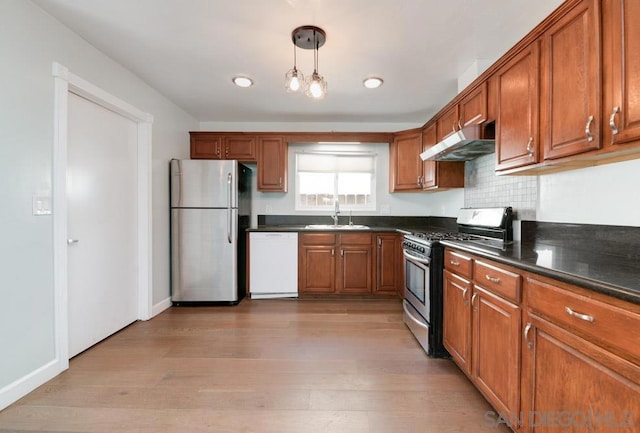 kitchen featuring stainless steel appliances, hanging light fixtures, sink, and light wood-type flooring