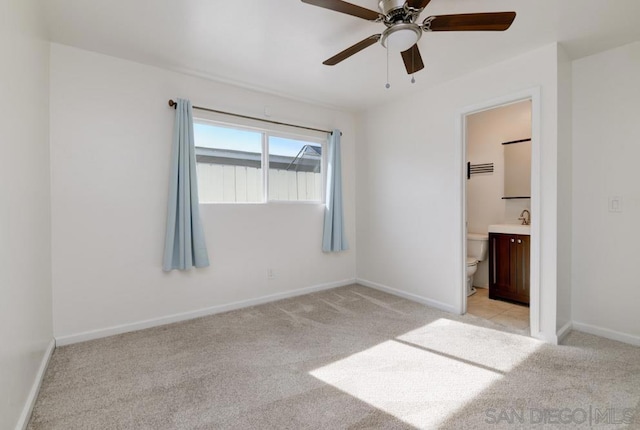 unfurnished bedroom with connected bathroom, sink, light colored carpet, and ceiling fan