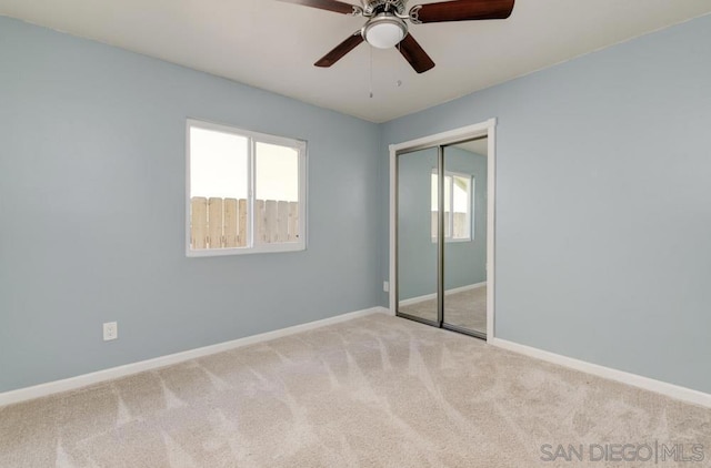 unfurnished bedroom with multiple windows, light colored carpet, a closet, and ceiling fan