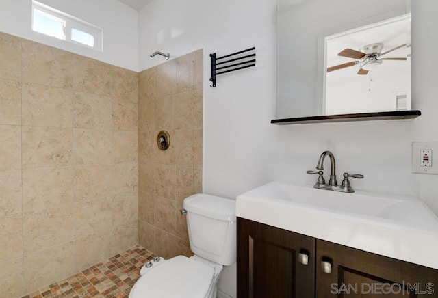 bathroom featuring ceiling fan, vanity, toilet, and a tile shower