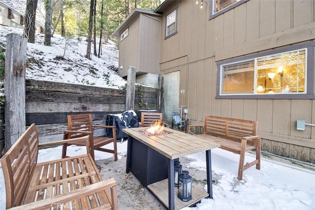 snow covered patio featuring a fire pit