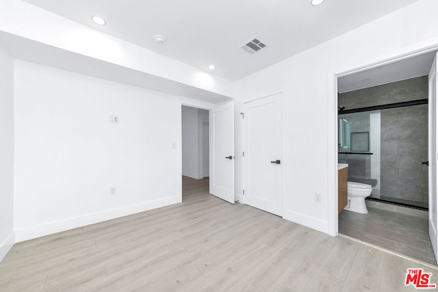 unfurnished bedroom with a closet, ensuite bathroom, and light hardwood / wood-style flooring