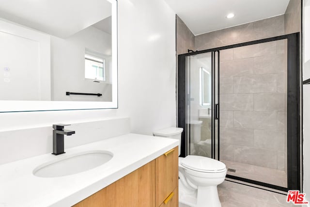 bathroom featuring vanity, toilet, a shower with shower door, and tile patterned flooring