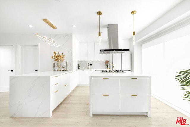 kitchen with white cabinetry, island range hood, hanging light fixtures, light hardwood / wood-style flooring, and gas cooktop