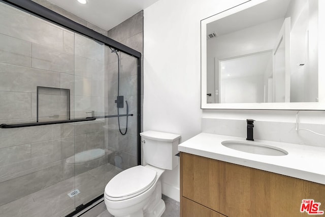 bathroom with vanity, a shower with door, and toilet