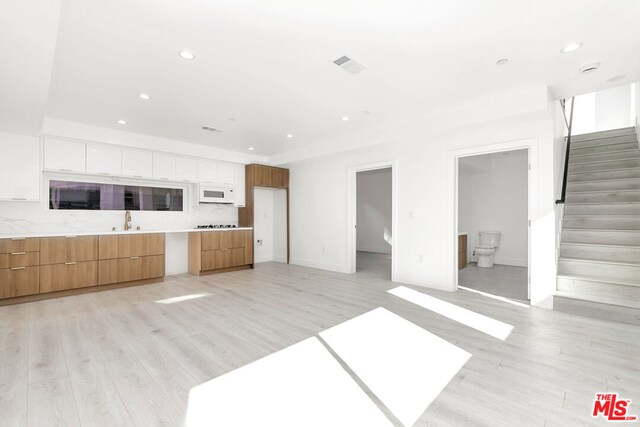 unfurnished living room featuring sink and light hardwood / wood-style flooring