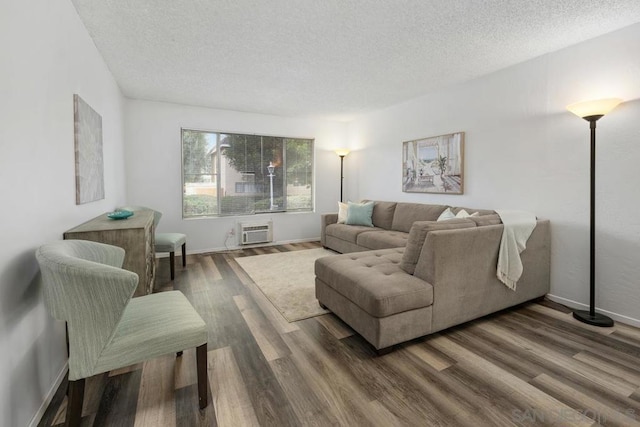 living room with dark wood-type flooring, a textured ceiling, and a wall unit AC