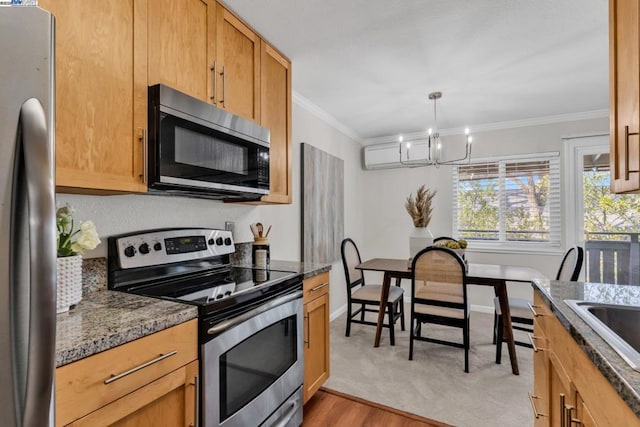 kitchen with crown molding, appliances with stainless steel finishes, decorative light fixtures, and dark stone counters